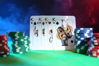 Photo of Poker chips and playing cards on green table