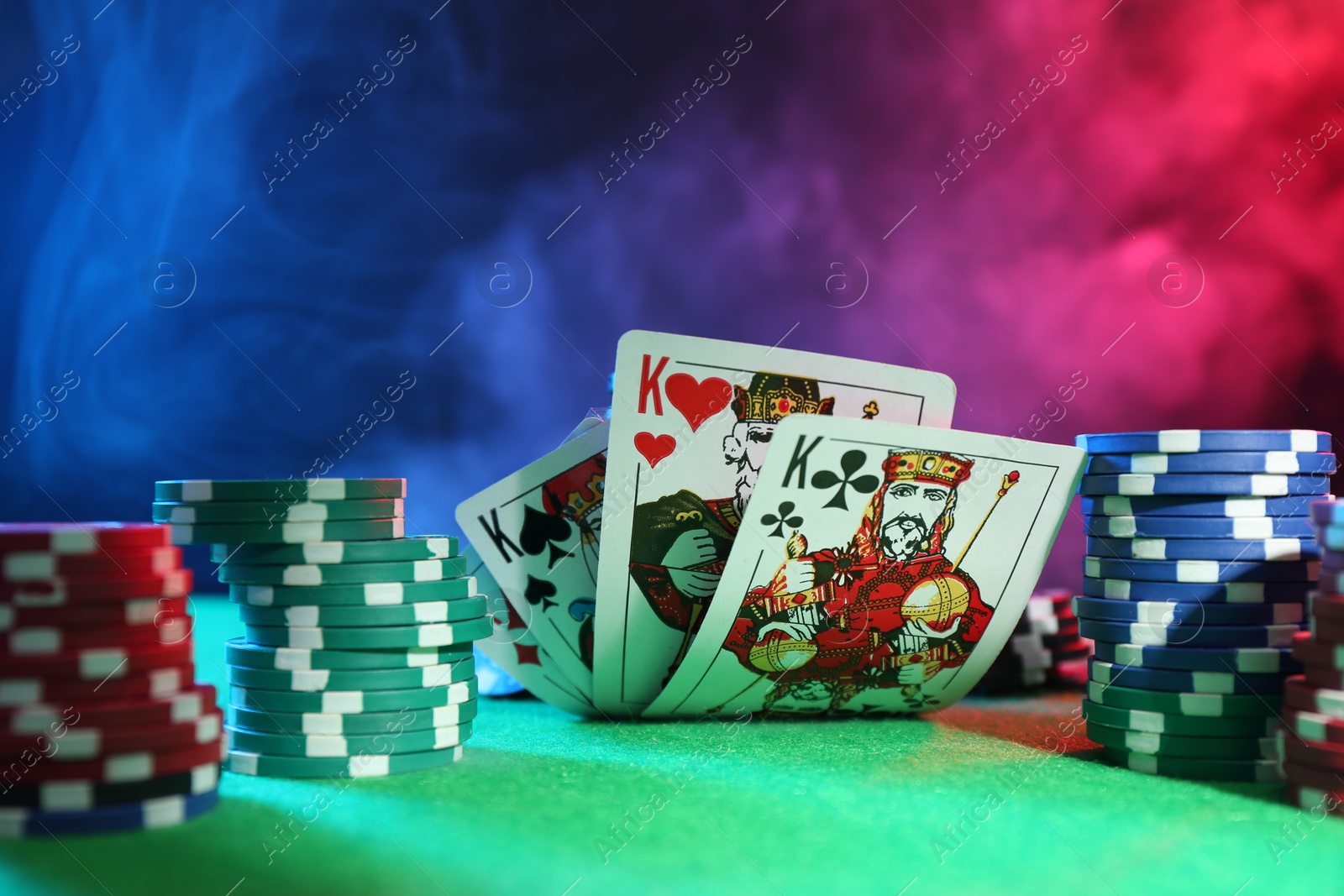 Photo of Poker chips and playing cards on green table