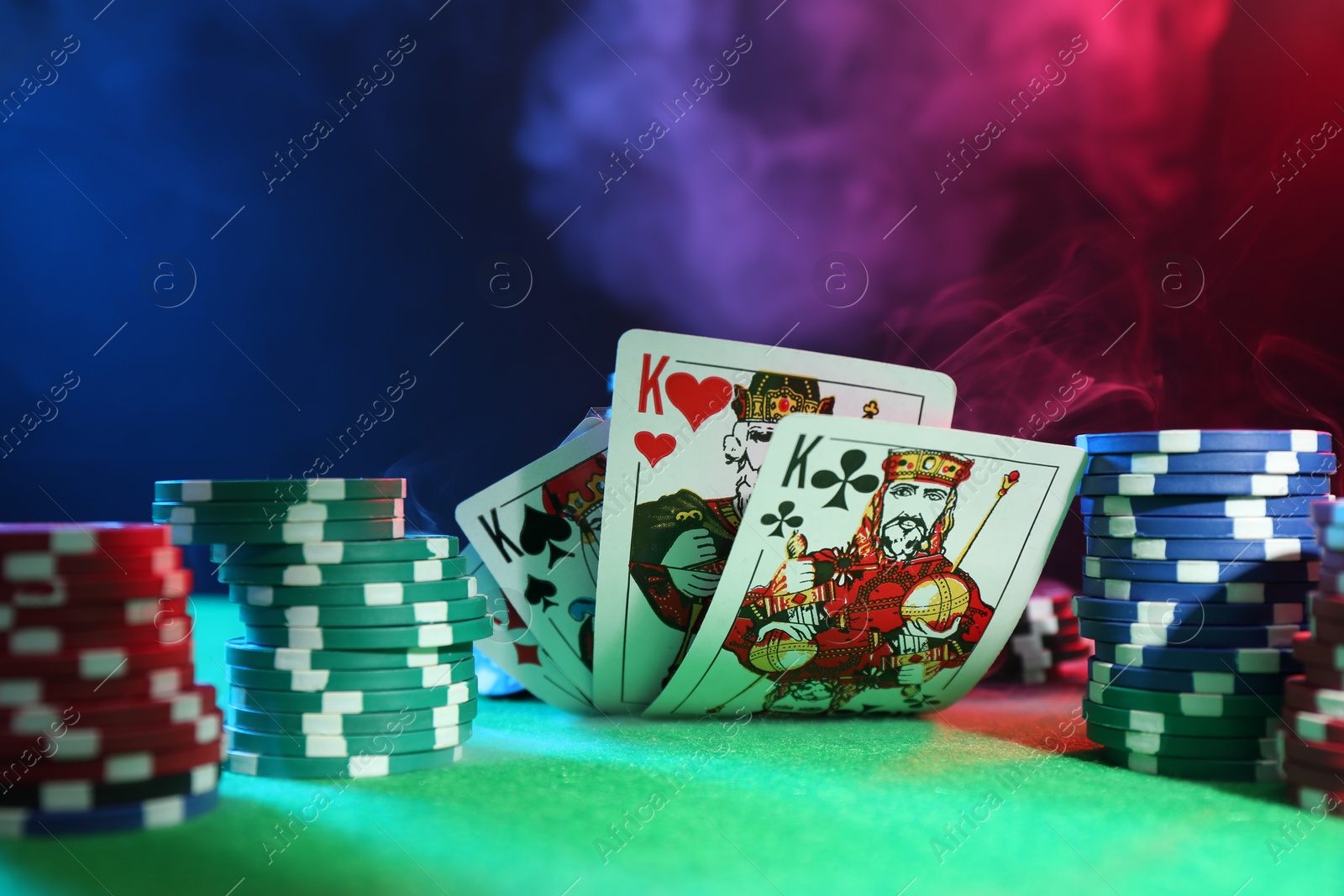 Photo of Poker chips and playing cards on green table