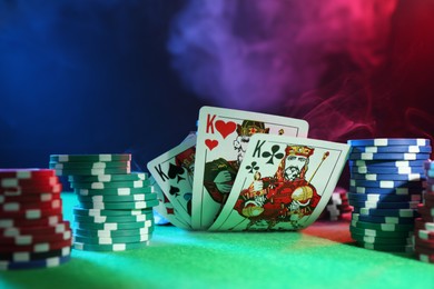 Photo of Poker chips and playing cards on green table