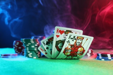 Photo of Poker chips and playing cards on green table, closeup