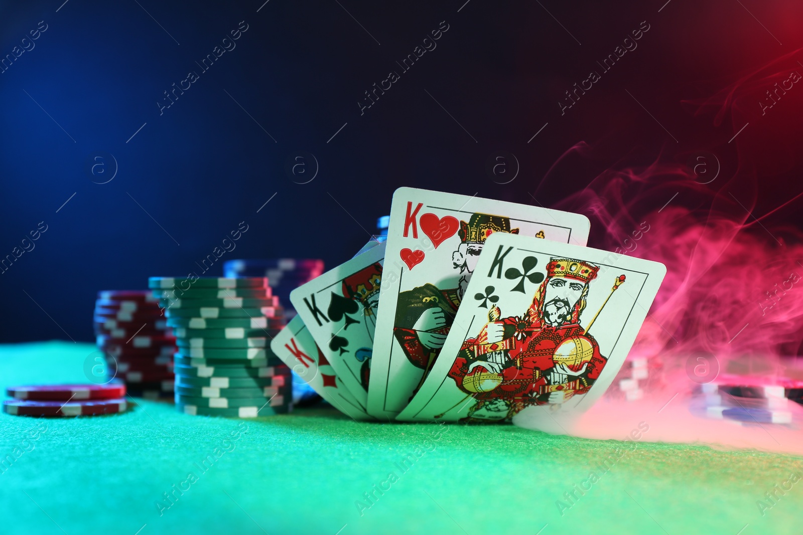 Photo of Poker chips and playing cards on green table, closeup