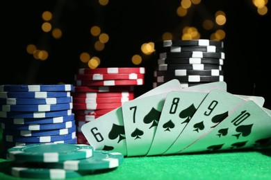 Photo of Poker chips and playing cards on green table, closeup