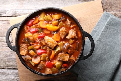 Delicious stew with vegetables in pot on wooden table, top view