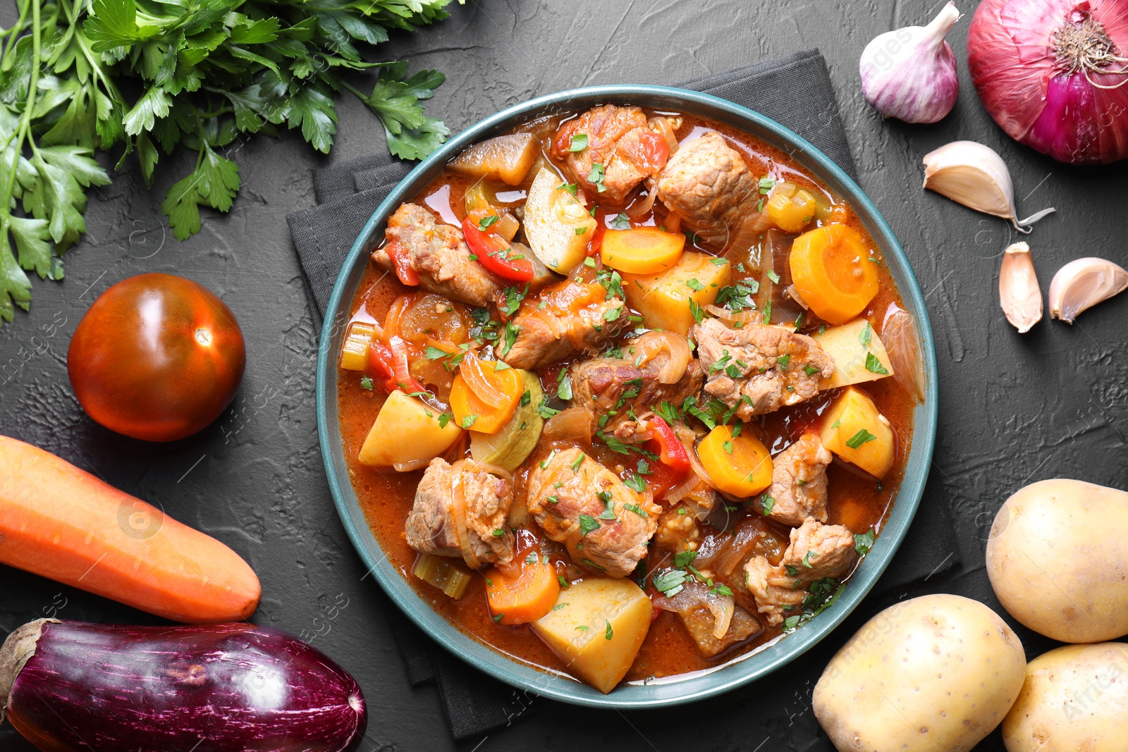 Photo of Delicious stew and different ingredients on black table, flat lay