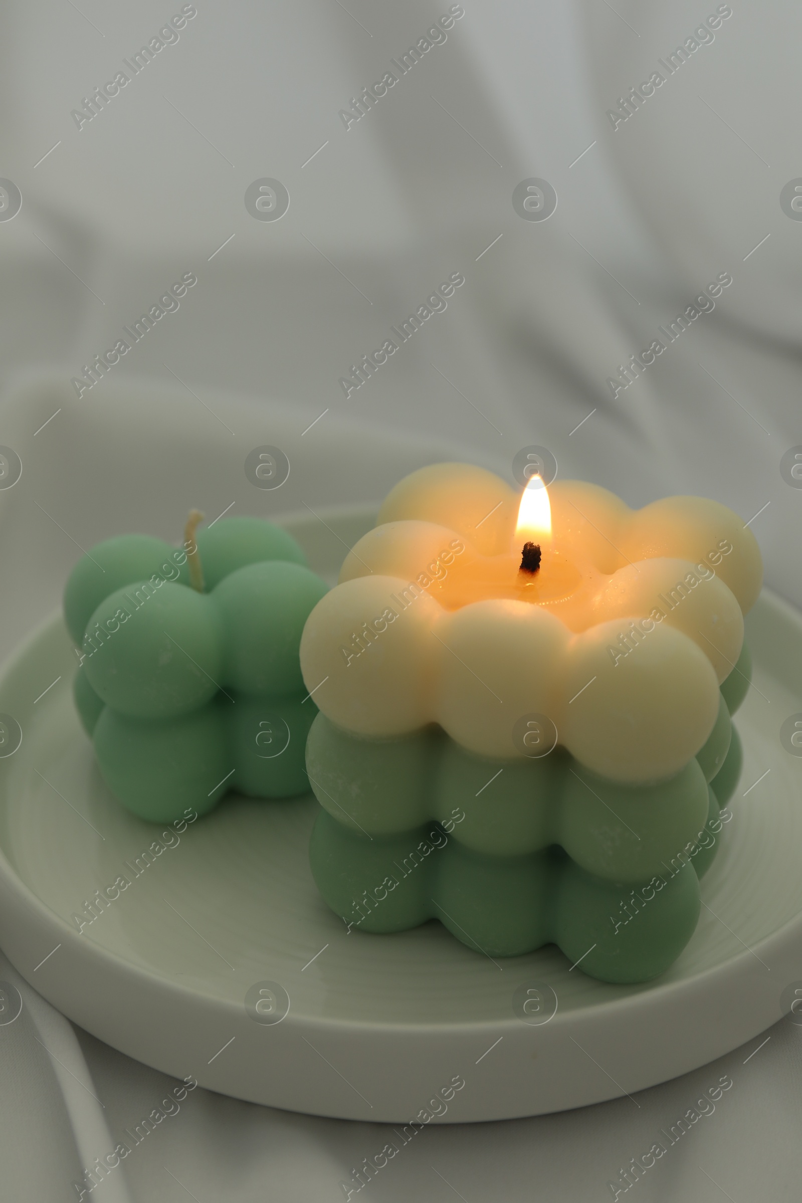 Photo of Stylish bubble candles on white cloth, closeup