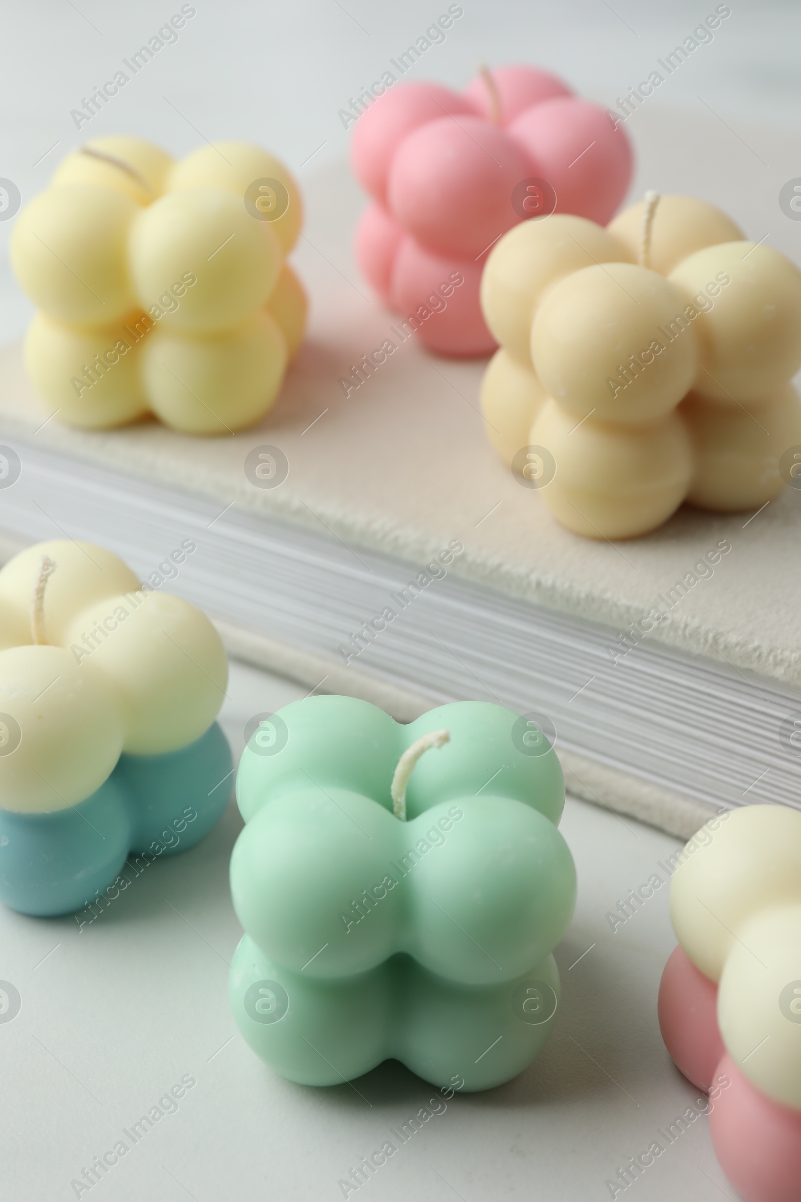 Photo of Different stylish bubble candles and book on white table, closeup