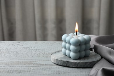 Photo of Burning bubble candle on grey wooden table. Space for text