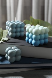 Photo of Stylish bubble candles on stack of books, closeup