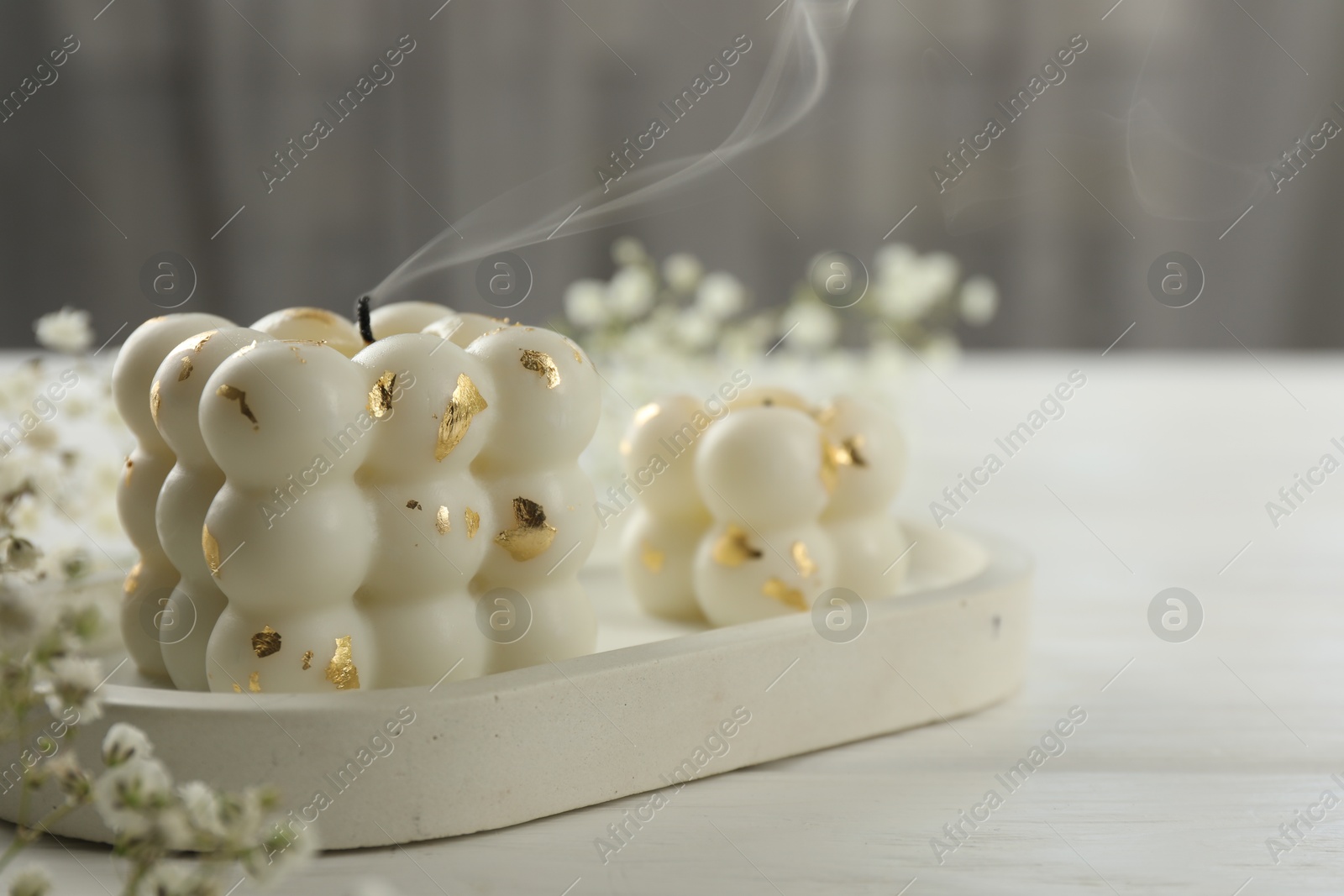 Photo of Stylish bubble candles and gypsophila flowers on white wooden table, closeup. Space for text