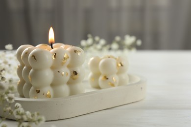 Photo of Stylish bubble candles and gypsophila flowers on white wooden table, closeup. Space for text