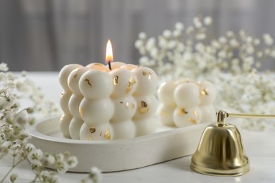 Photo of Stylish bubble candles, snuffer and gypsophila flowers on white wooden table, closeup