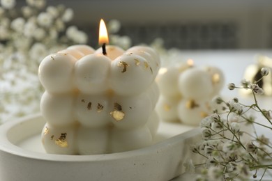 Photo of Stylish bubble candles and gypsophila flowers on table, closeup