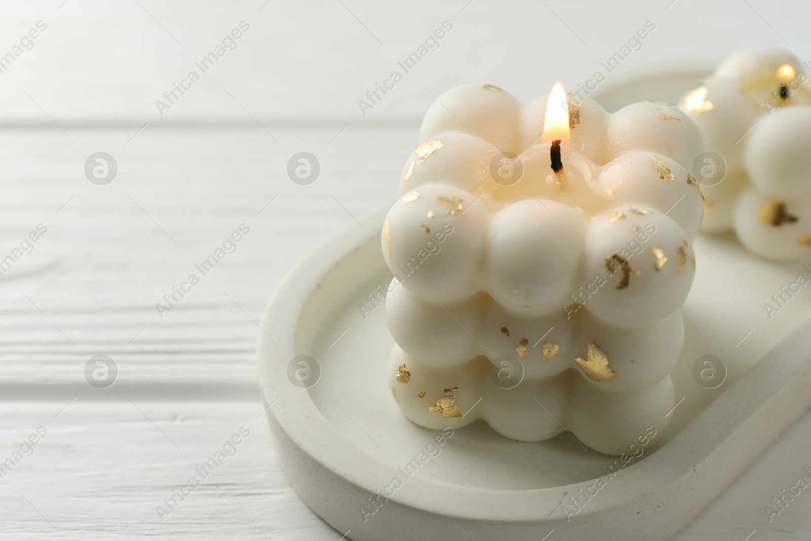 Photo of Stylish bubble candles on white wooden table, closeup. Space for text