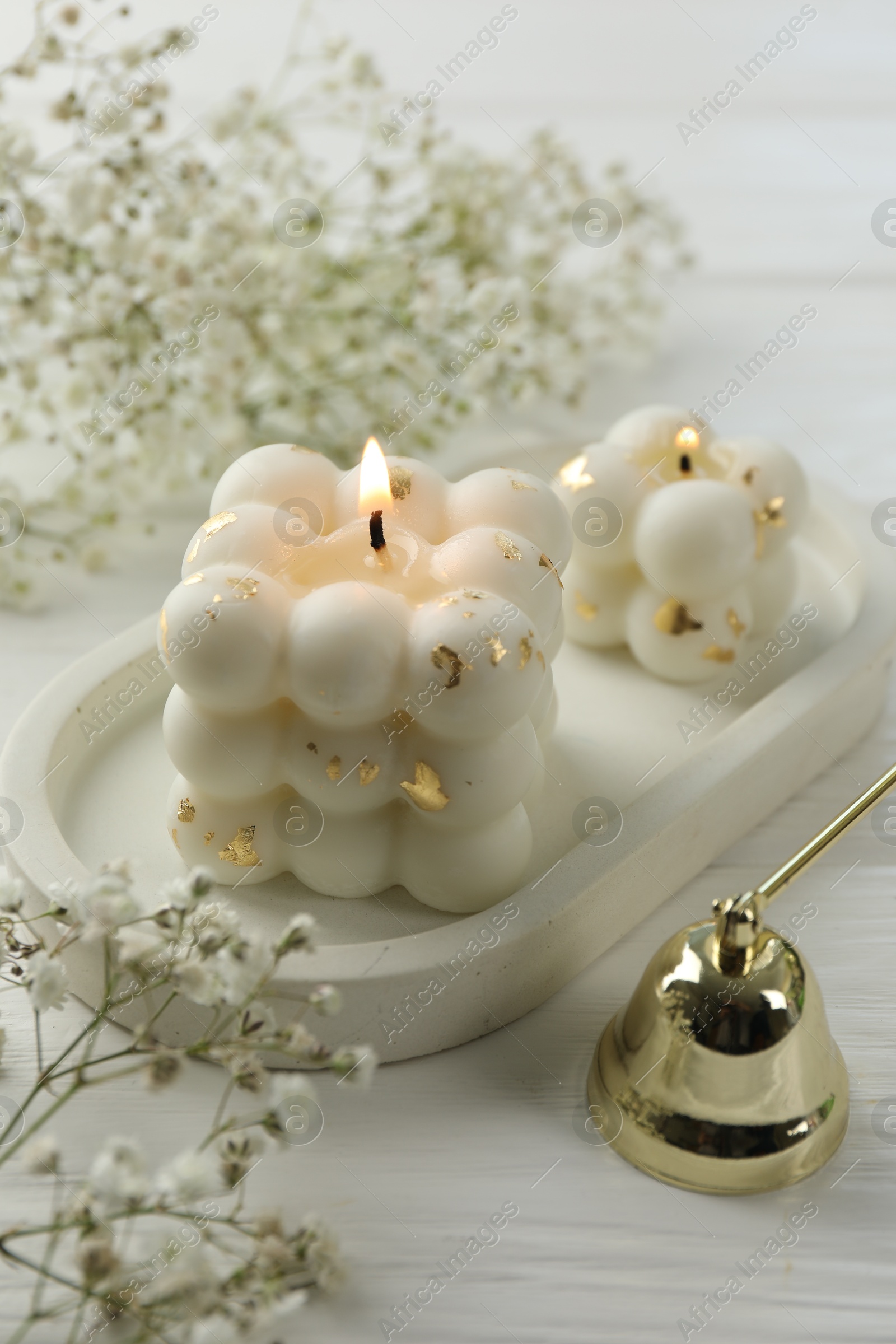 Photo of Stylish bubble candles, snuffer and gypsophila flowers on white wooden table