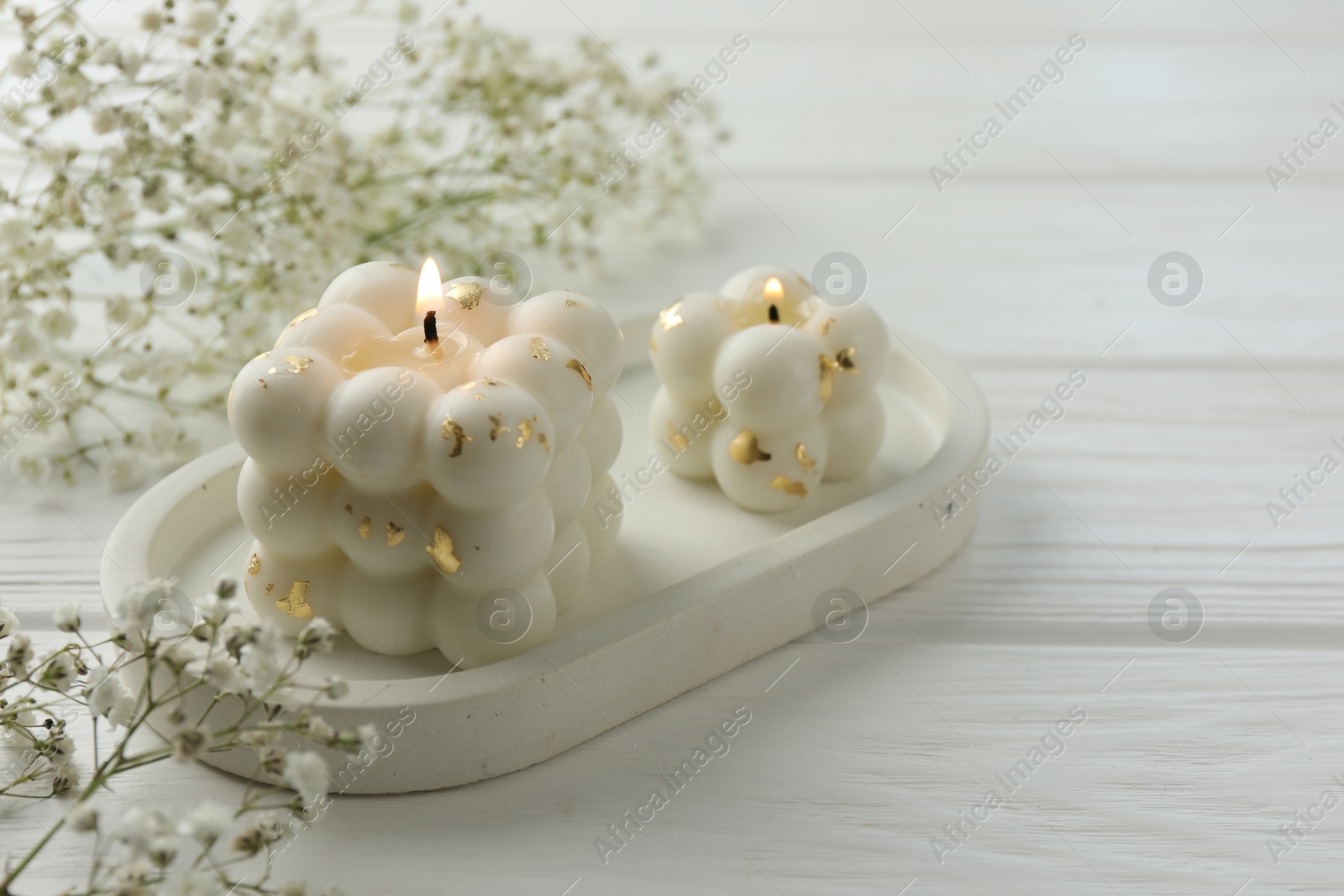 Photo of Stylish bubble candles and gypsophila flowers on white wooden table, closeup. Space for text