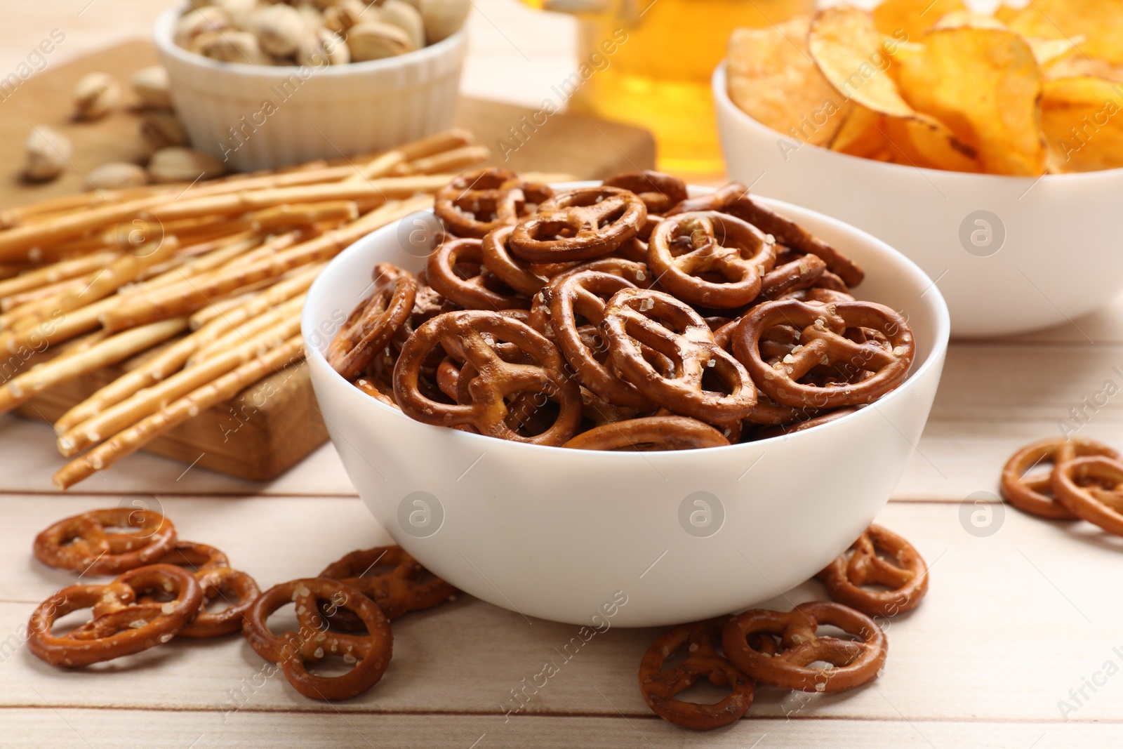 Photo of Delicious pretzel crackers and other snacks on white wooden table, closeup