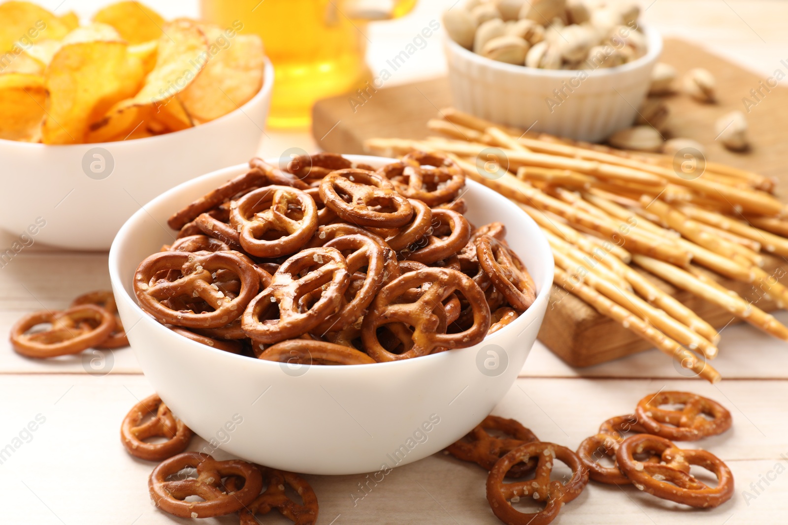 Photo of Delicious pretzel crackers and other snacks on white wooden table, closeup