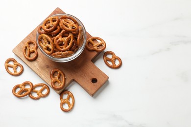 Photo of Delicious salty pretzel crackers on white table, top view. Space for text