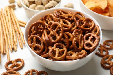 Photo of Delicious pretzel crackers and other snacks on white table, closeup