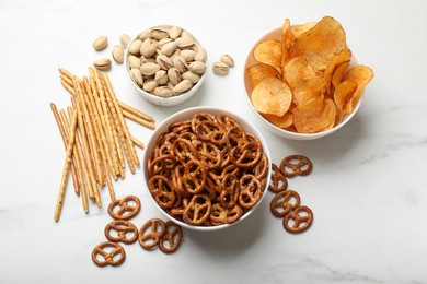 Photo of Delicious pretzel crackers and other snacks on white table, flat lay