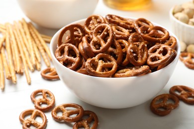 Photo of Delicious pretzel crackers and other snacks on white table, closeup