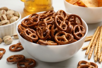 Photo of Delicious pretzel crackers and other snacks on white table, closeup