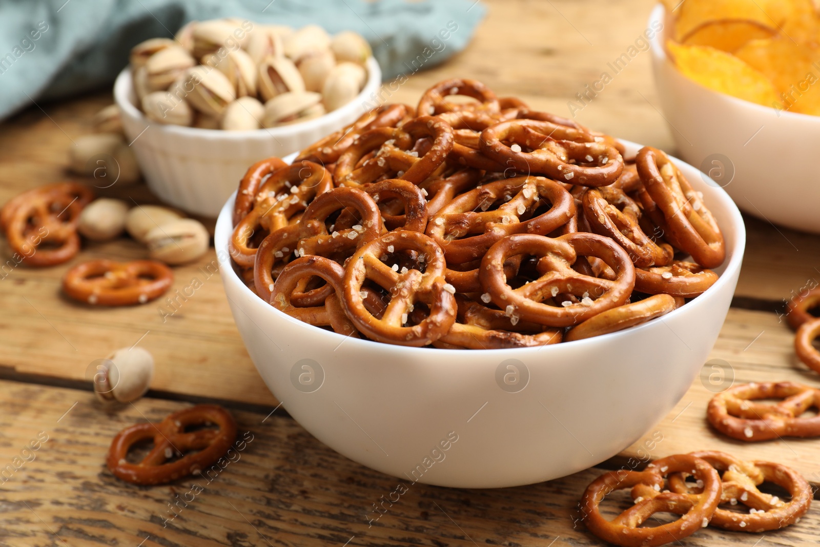 Photo of Delicious pretzel crackers and other snacks on wooden table, closeup