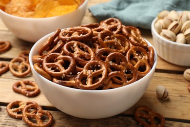 Photo of Delicious pretzel crackers and other snacks on wooden table, closeup