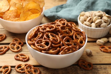 Photo of Delicious pretzel crackers and other snacks on wooden table, closeup