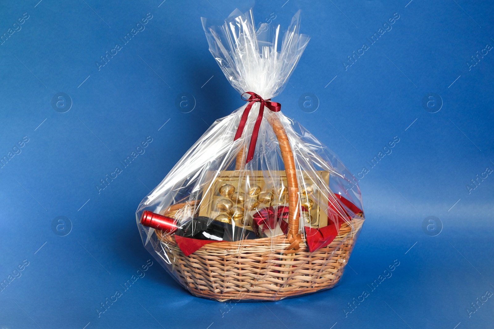 Photo of Wicker gift basket with wine on blue background