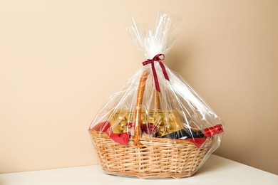 Wicker gift basket on table against beige background