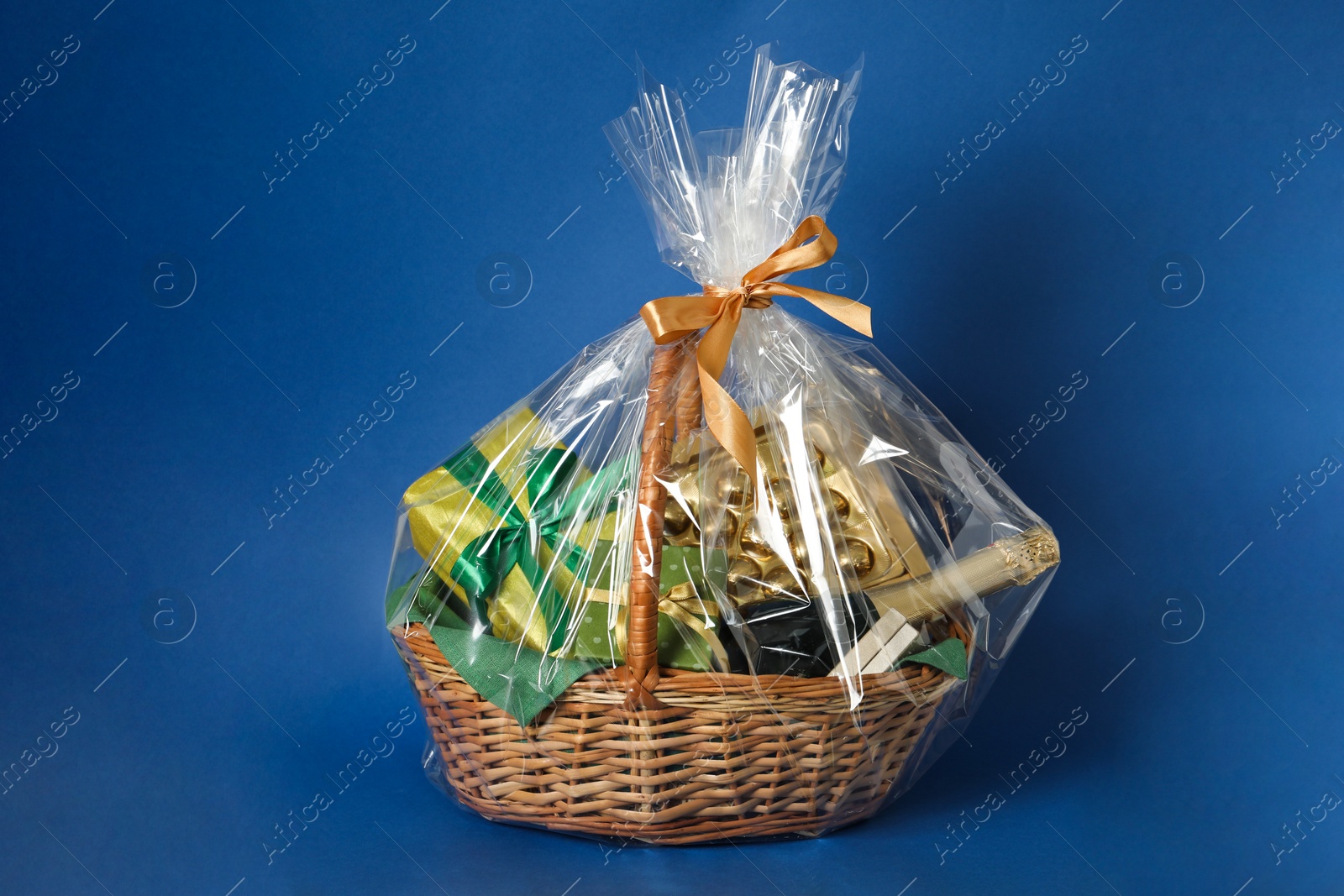 Photo of Wicker gift basket with wine on blue background