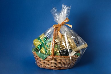 Photo of Wicker gift basket with wine on blue background