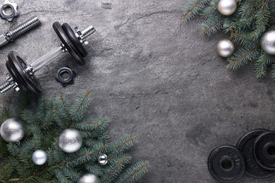 Photo of Barbell, dumbbell parts and Christmas decor on grey background, flat lay. Space for text