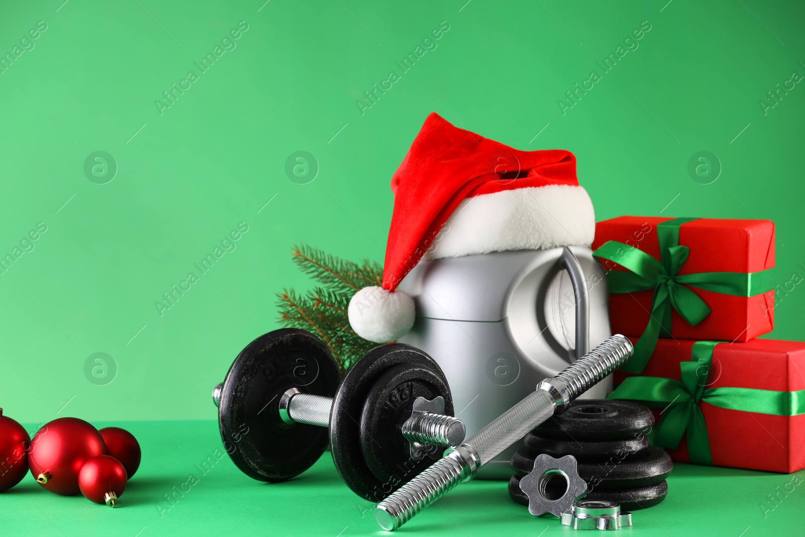 Photo of Dumbbells, container with supplement and Christmas decor on green background. Space for text