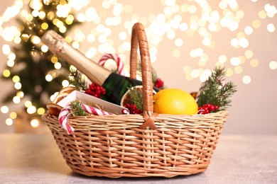 Photo of Wicker gift basket with sparkling wine and Christmas decor on light textured table