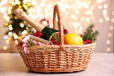 Photo of Wicker gift basket with sparkling wine and Christmas decor on light textured table