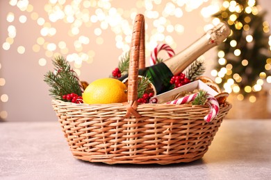 Wicker gift basket with sparkling wine and Christmas decor on light textured table