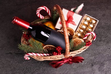 Photo of Wicker gift basket with wine and Christmas decor on grey textured table