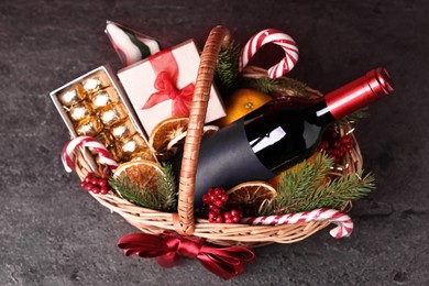 Photo of Wicker gift basket with wine and Christmas decor on grey textured table