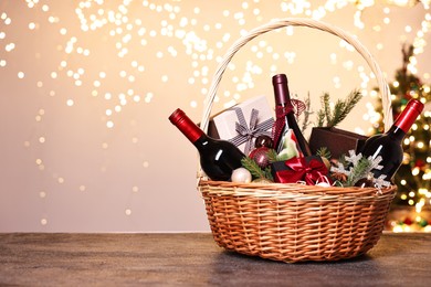 Photo of Wicker gift basket with wine and Christmas decor on grey textured table, space for text