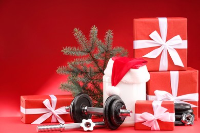 Photo of Dumbbells, container with supplement and Christmas decor on red background. Space for text