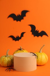 Photo of Halloween celebration. Black paper bats, spiders pumpkins and podium on orange background