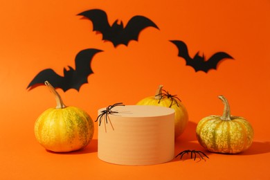 Photo of Halloween celebration. Black paper bats, spiders pumpkins and podium on orange background