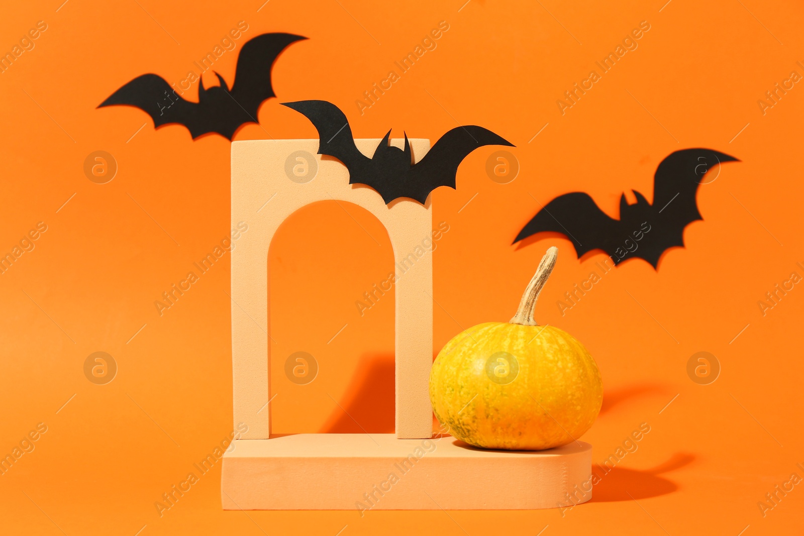 Photo of Halloween celebration. Black paper bats, pumpkin and geometric figures on orange background