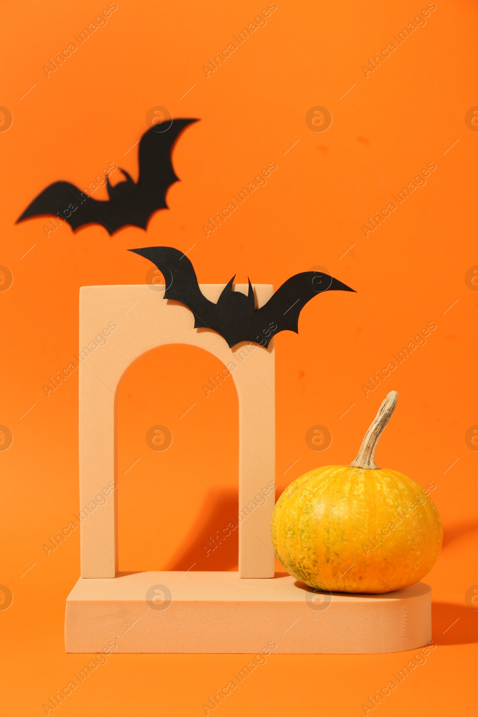 Photo of Halloween celebration. Black paper bats, pumpkin and geometric figures on orange background