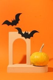 Halloween celebration. Black paper bats, pumpkin and geometric figures on orange background