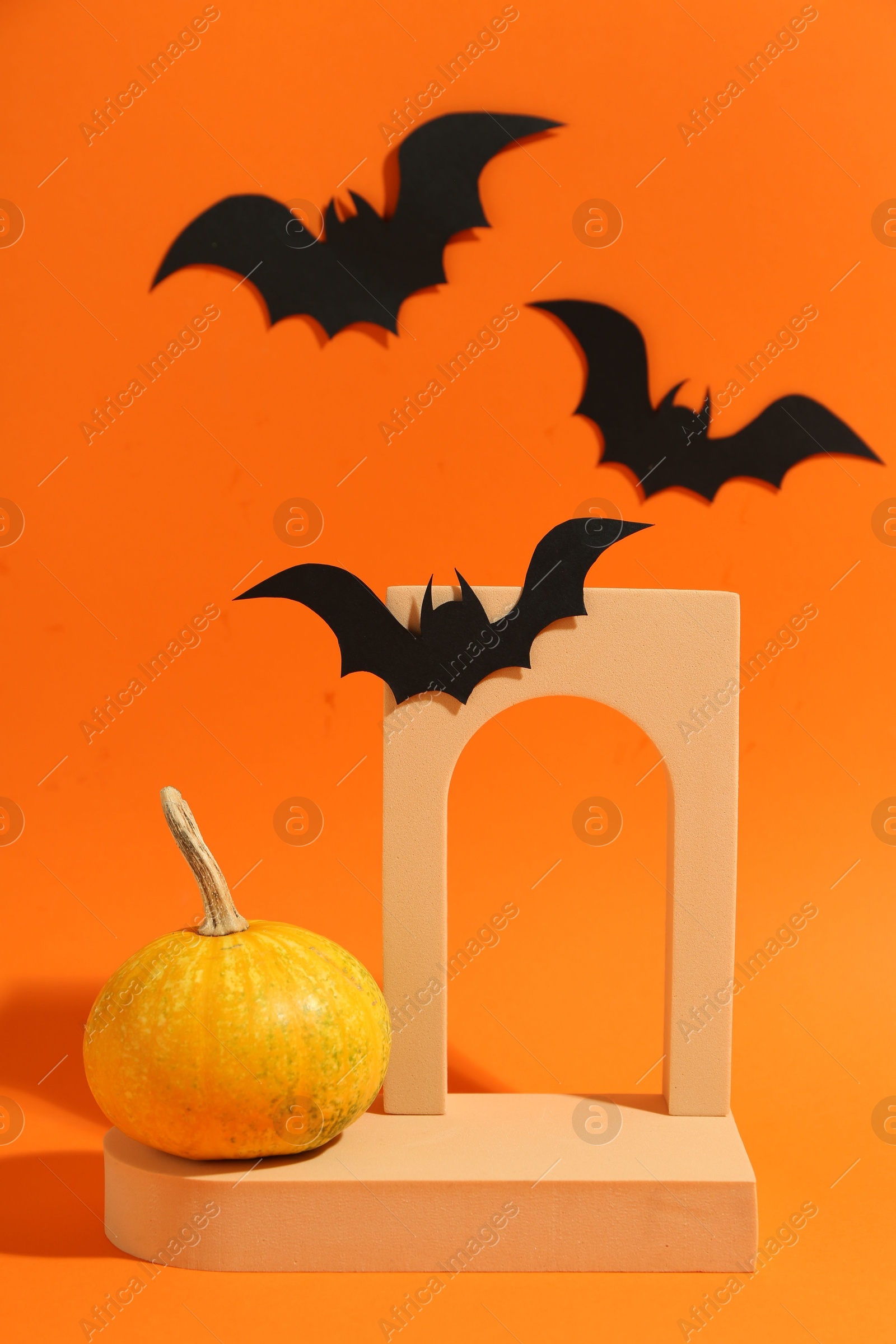 Photo of Halloween celebration. Black paper bats, pumpkin and geometric figures on orange background