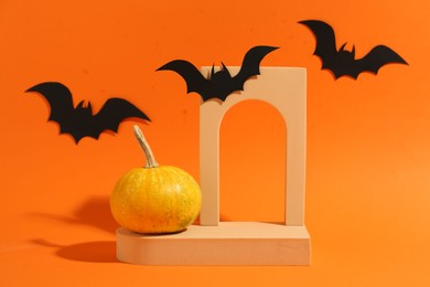 Halloween celebration. Black paper bats, pumpkin and geometric figures on orange background